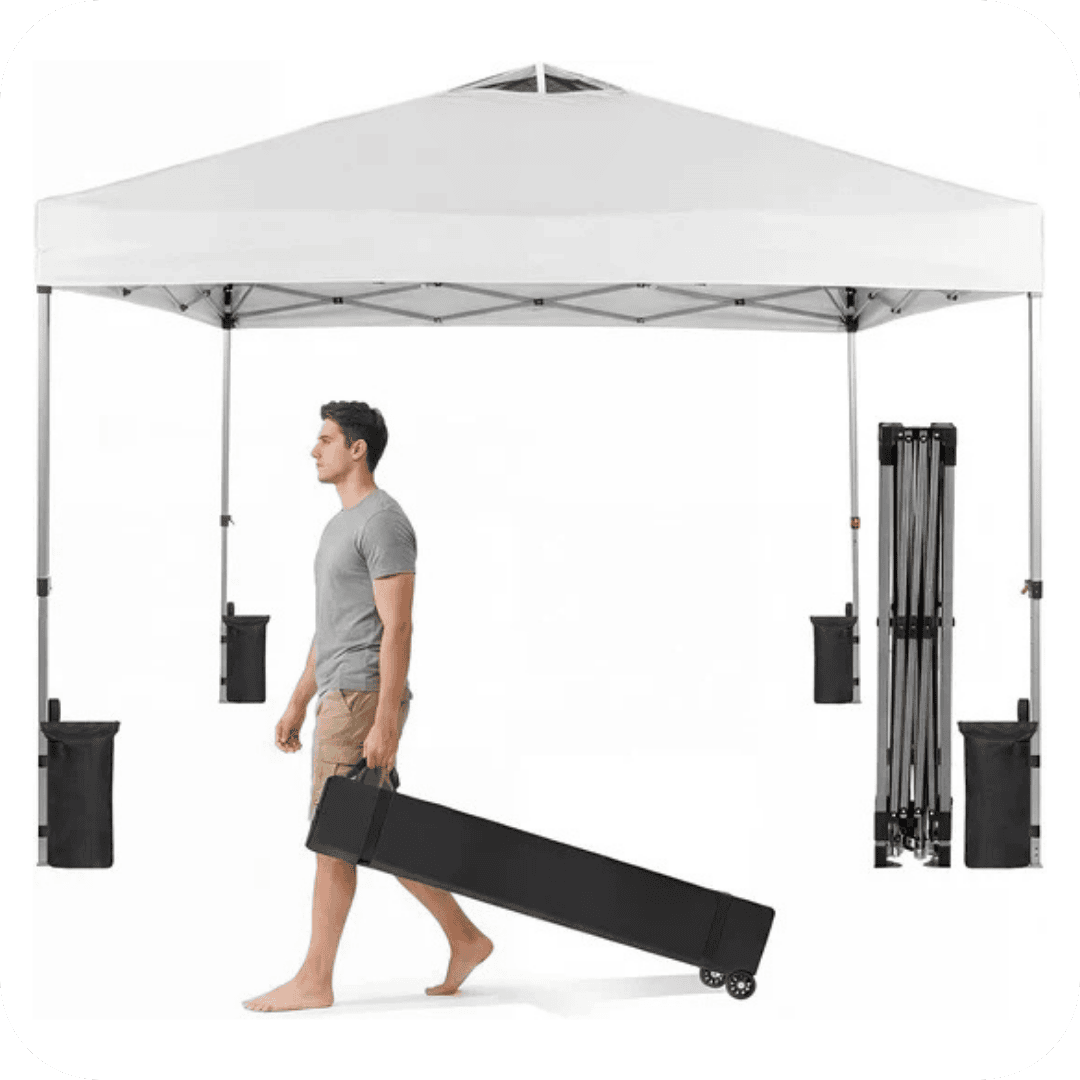 Man in gray t-shirt and shorts pulls a black carrying case on wheels under a white pop-up canopy tent. A folded frame is visible to the right of the tent.