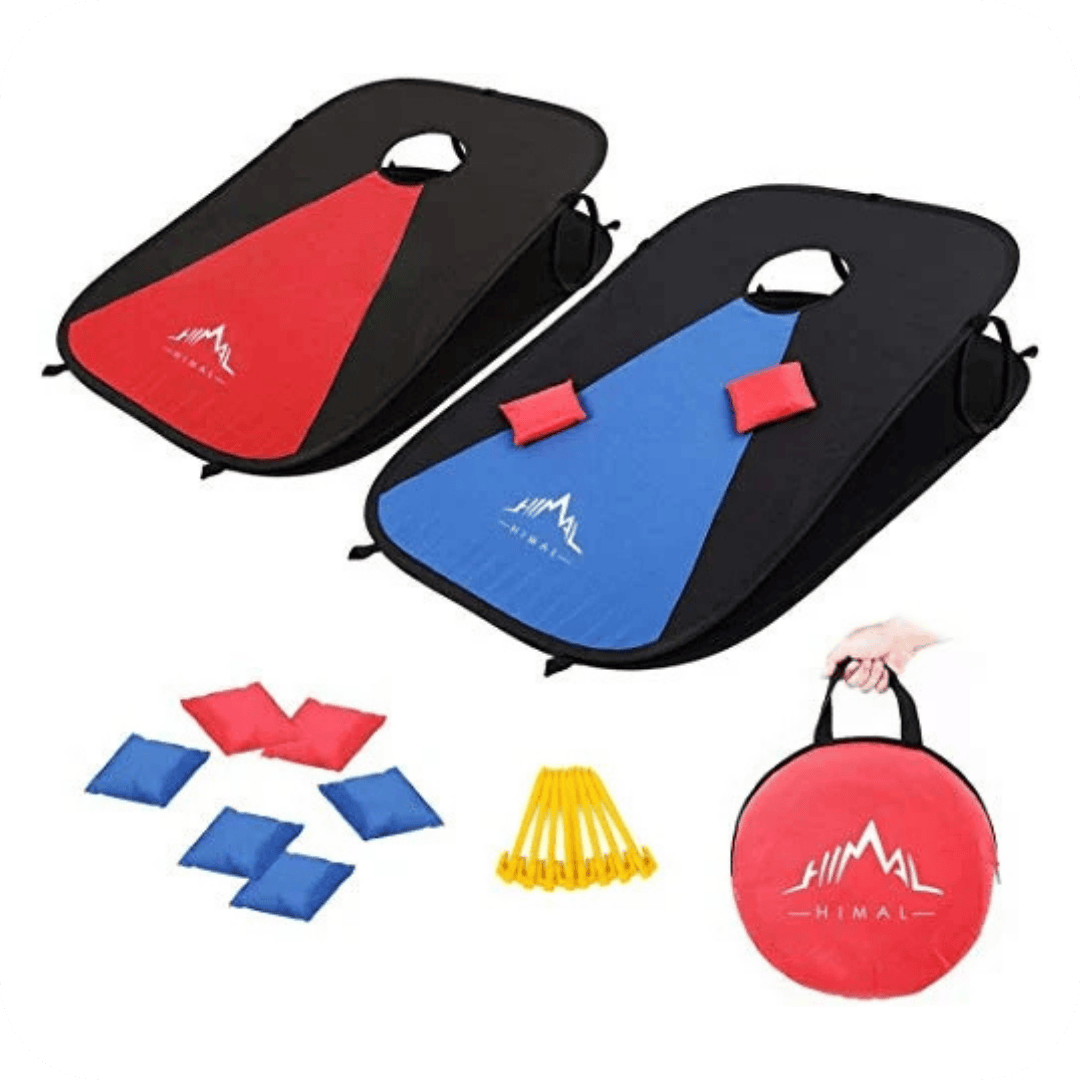 Two portable cornhole boards, one with a red target and one blue, eight bean bags, yellow stakes, and a red carrying bag with a mountain logo are shown. A hand holds the carrying bag on the right side.